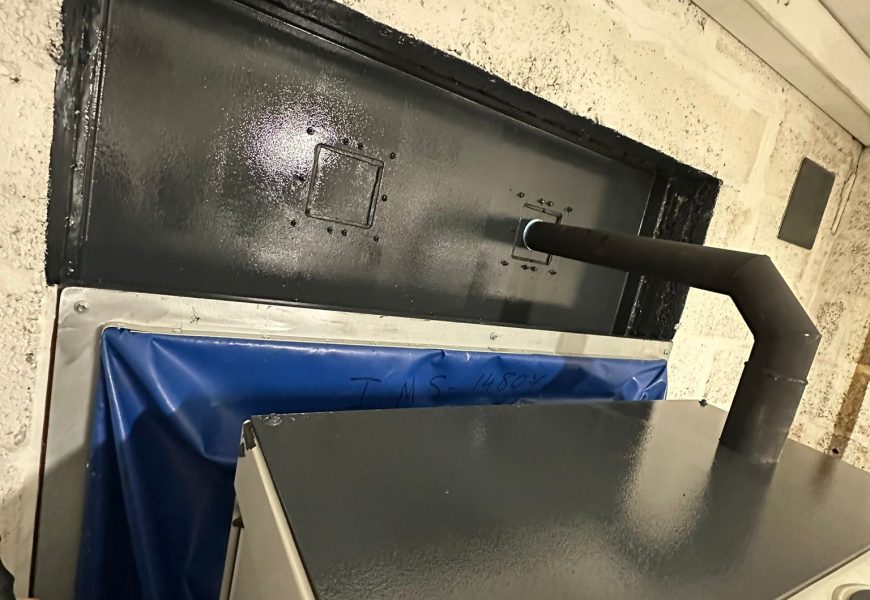 Installed exhaust pipe assembly and weather louvre at a UK fire station.